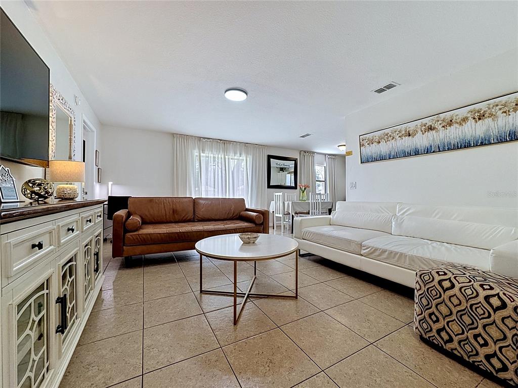A living room features a brown leather sofa, a white sofa, and a round coffee table — 1716 TERRY CIRCLE NE, WINTER HAVEN, FL