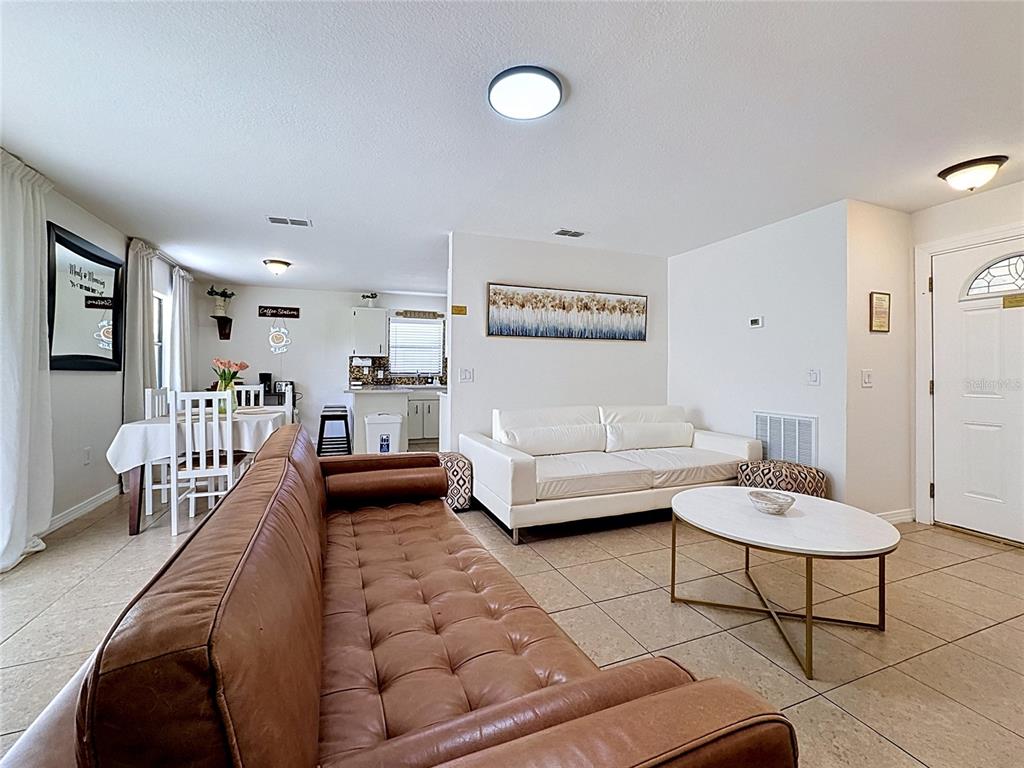 A living room with a brown leather sofa, white couch, and dining area in the background — 1716 TERRY CIRCLE NE, WINTER HAVEN, FL