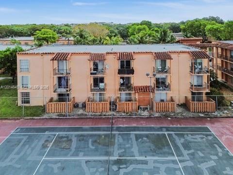 An exterior view of a multi-story peach-colored apartment building adjacent to a tennis court — 7155 Miami Lakes Dr # P16, Miami Lakes FL 33014, MIAMI LAKES, FL