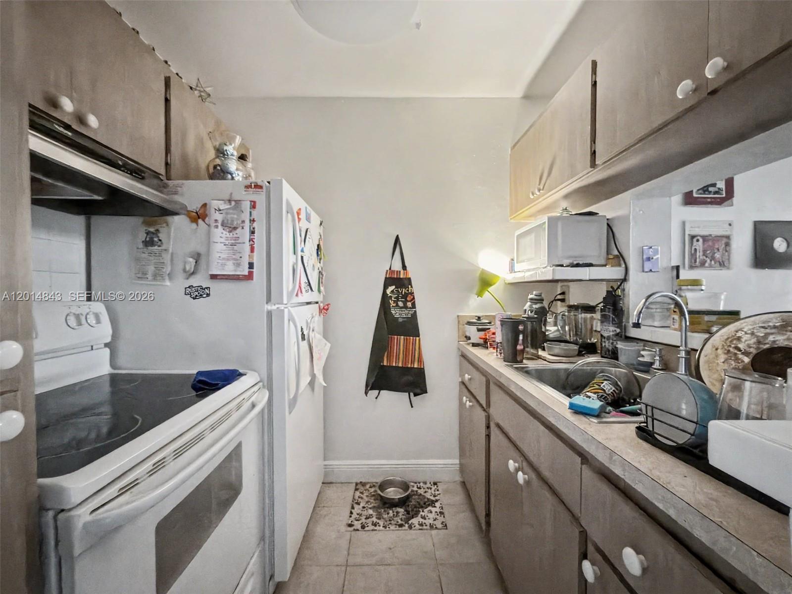 A galley kitchen features white appliances, wood-tone cabinets, and a stainless steel sink — 7155 Miami Lakes Dr # P16, Miami Lakes FL 33014, MIAMI LAKES, FL