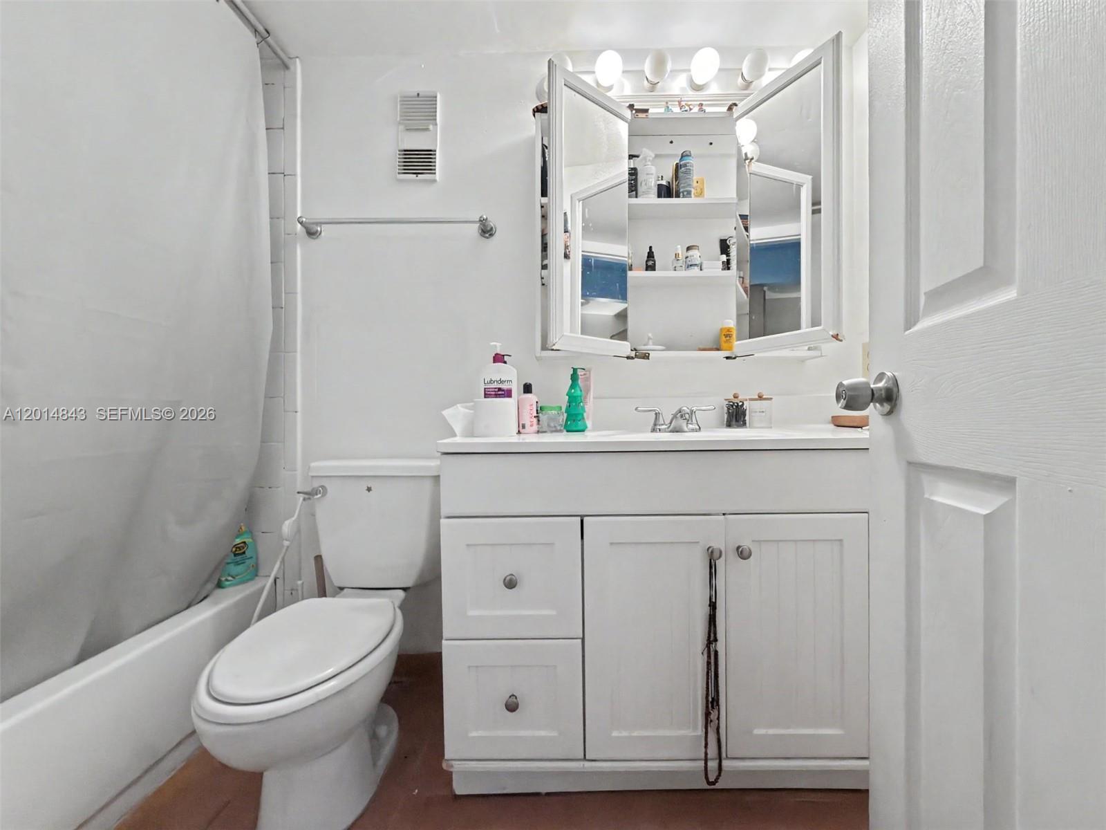 A white bathroom features a vanity with a medicine cabinet, a toilet, and a shower — 7155 Miami Lakes Dr # P16, Miami Lakes FL 33014, MIAMI LAKES, FL