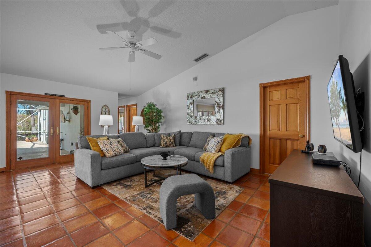 A living room features a grey sectional sofa, tile flooring, and a vaulted ceiling — 103 Olympus Circle, Jupiter FL 33477, JUPITER, FL