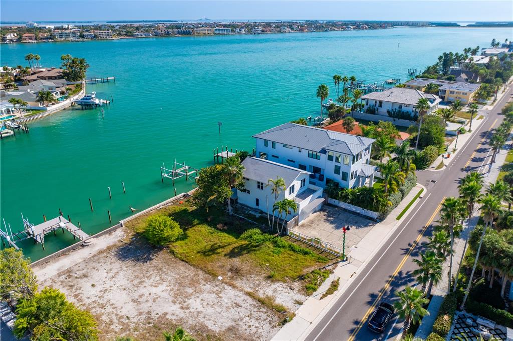 An aerial view shows a waterfront house with a dock and an adjacent vacant lot — 1805 PASS-A-GRILLE WAY, ST PETE BEACH, FL