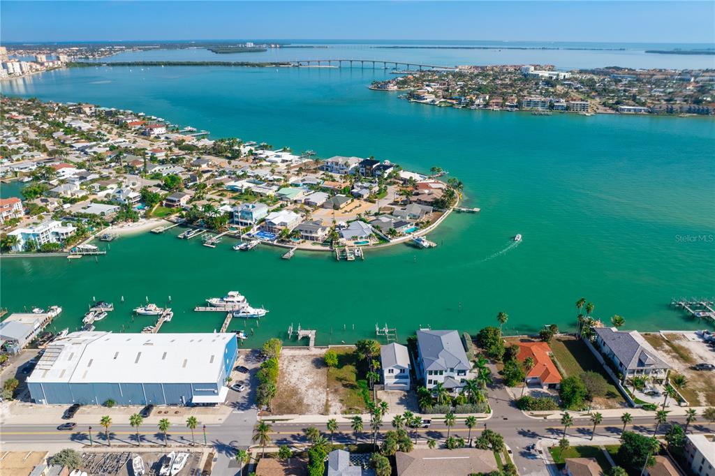 An aerial view shows a coastal neighborhood with houses, a marina, and a bridge — 1805 PASS-A-GRILLE WAY, ST PETE BEACH, FL