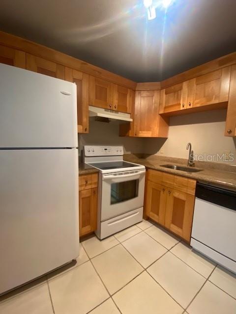 A kitchen features light wood cabinets, white appliances, and beige tile flooring — 3914 NEPTUNE STREET UNIT 1, TAMPA, FL