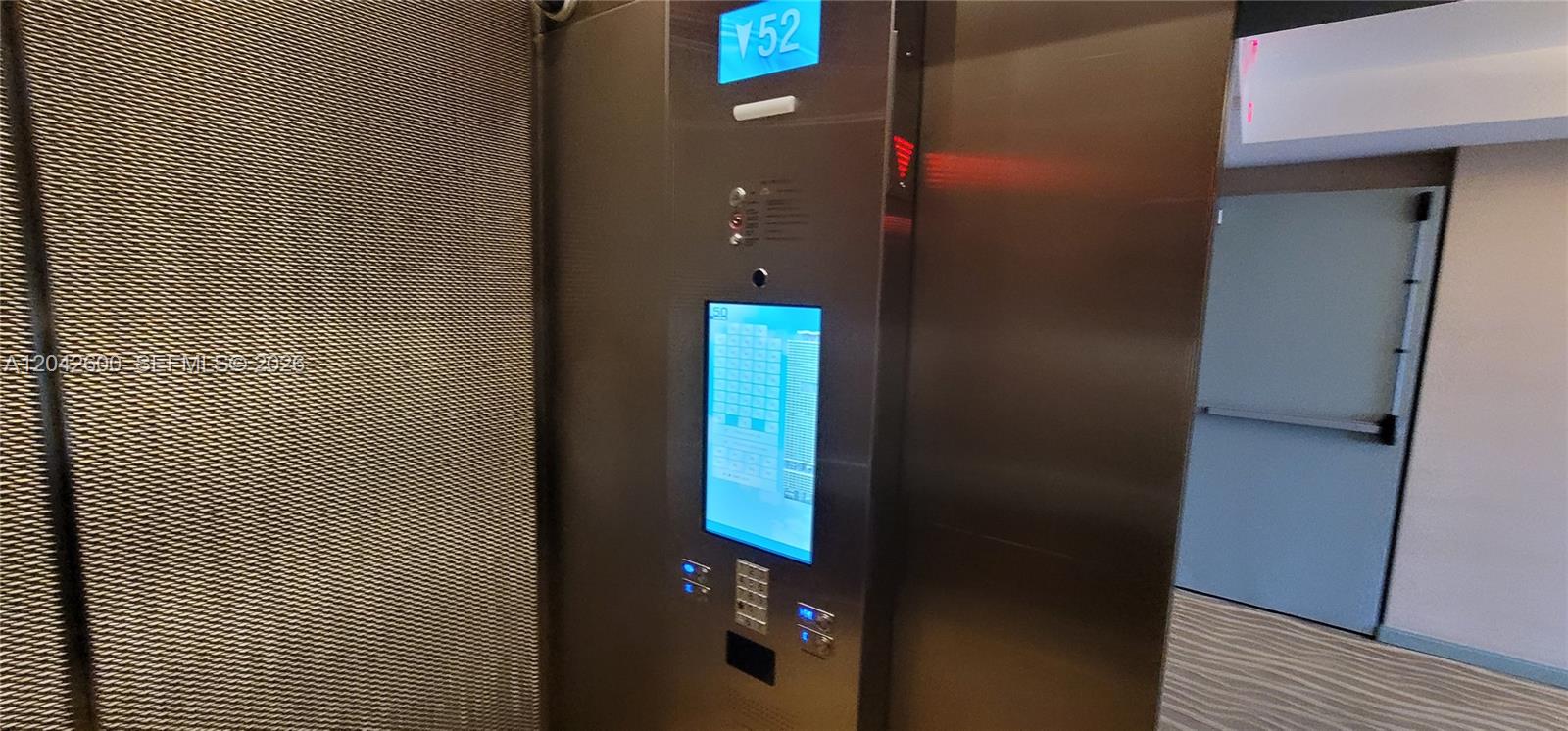 An elevator interior features a digital floor display, a touchscreen control panel, and metal walls — 50 Biscayne Blvd # 5202, Miami FL 33132, MIAMI, FL