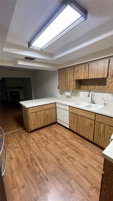 A kitchen features wood cabinets, white countertops, a dishwasher, and wood-look flooring — 1702 NE 38TH AVENUE, OCALA, FL