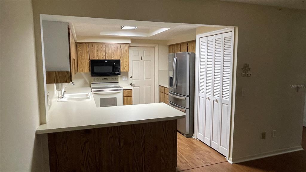 A kitchen features wood cabinets, white countertops, stainless steel appliances, and a white door — 1702 NE 38TH AVENUE, OCALA, FL