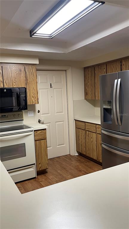 A kitchen features wood cabinets, a white stove, a microwave, and a stainless steel refrigerator — 1702 NE 38TH AVENUE, OCALA, FL