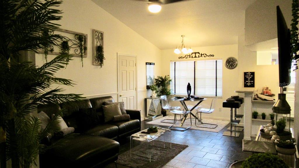 A living room and dining area with a black leather sofa, tile floors, and chandelier — 21103 PATIO VIEW COURT UNIT 3302, LUTZ, FL