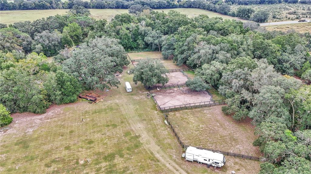 An aerial view shows a rural property with fenced pastures, mature trees, and two trailers — 19597 SE 70TH LANE, MORRISTON, FL
