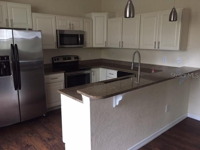 A kitchen features white cabinets, stainless steel appliances, and a granite-topped breakfast bar — 2608 E JEFFERSON STREET, ORLANDO, FL
