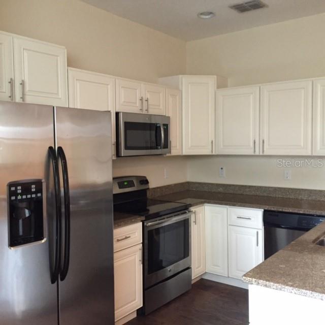 A kitchen features white cabinets, stainless steel appliances, and brown granite countertops — 2608 E JEFFERSON STREET, ORLANDO, FL