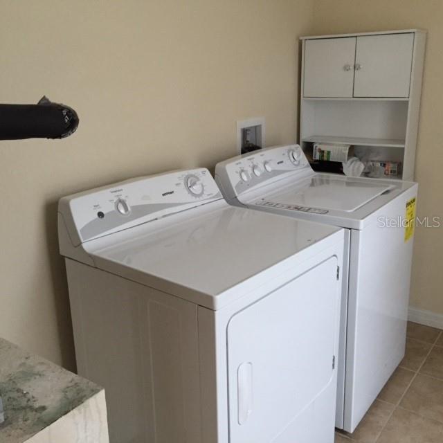 A laundry room features a white washer and dryer next to a wall-mounted storage cabinet — 2608 E JEFFERSON STREET, ORLANDO, FL