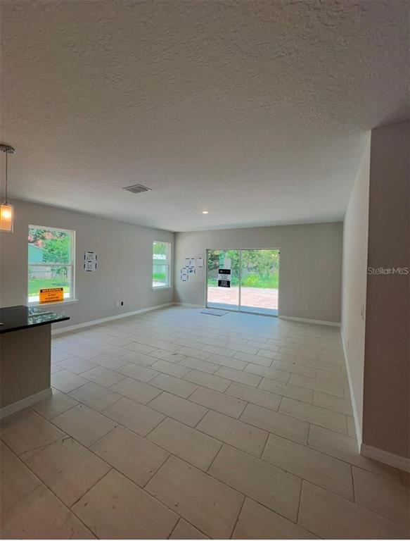 An open-concept living area features light-colored tile flooring, neutral walls, and sliding glass doors — 809 S LOCUST AVENUE, SANFORD, FL