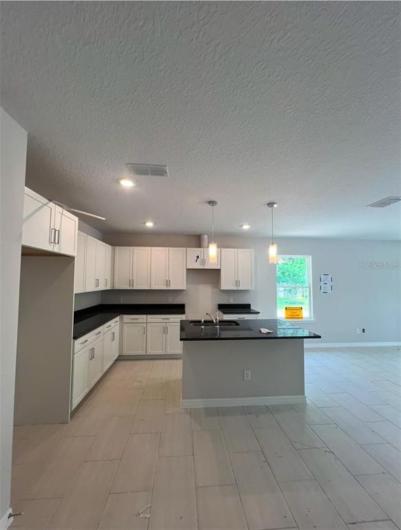 A kitchen features white cabinets, black countertops, a center island, and light-colored tile flooring — 809 S LOCUST AVENUE, SANFORD, FL