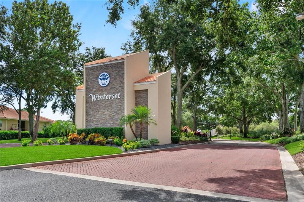 A stone and stucco entrance sign for Winterset stands beside a brick paved road — 3027 RICHMOND DRIVE, WINTER HAVEN, FL