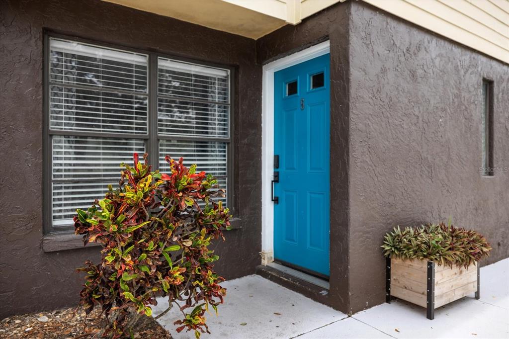 A bright blue front door is set into a dark brown stucco exterior wall — 960 HIGHLAND STREET UNIT A7, SARASOTA, FL