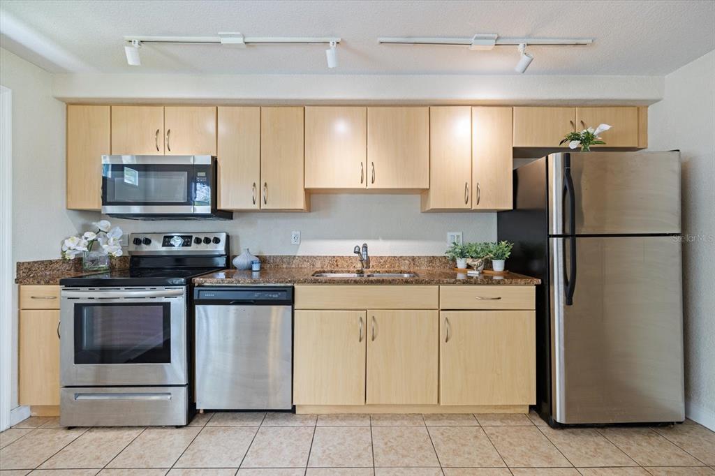 A kitchen features light wood cabinets, stainless steel appliances, and brown granite countertops — 960 HIGHLAND STREET UNIT A7, SARASOTA, FL