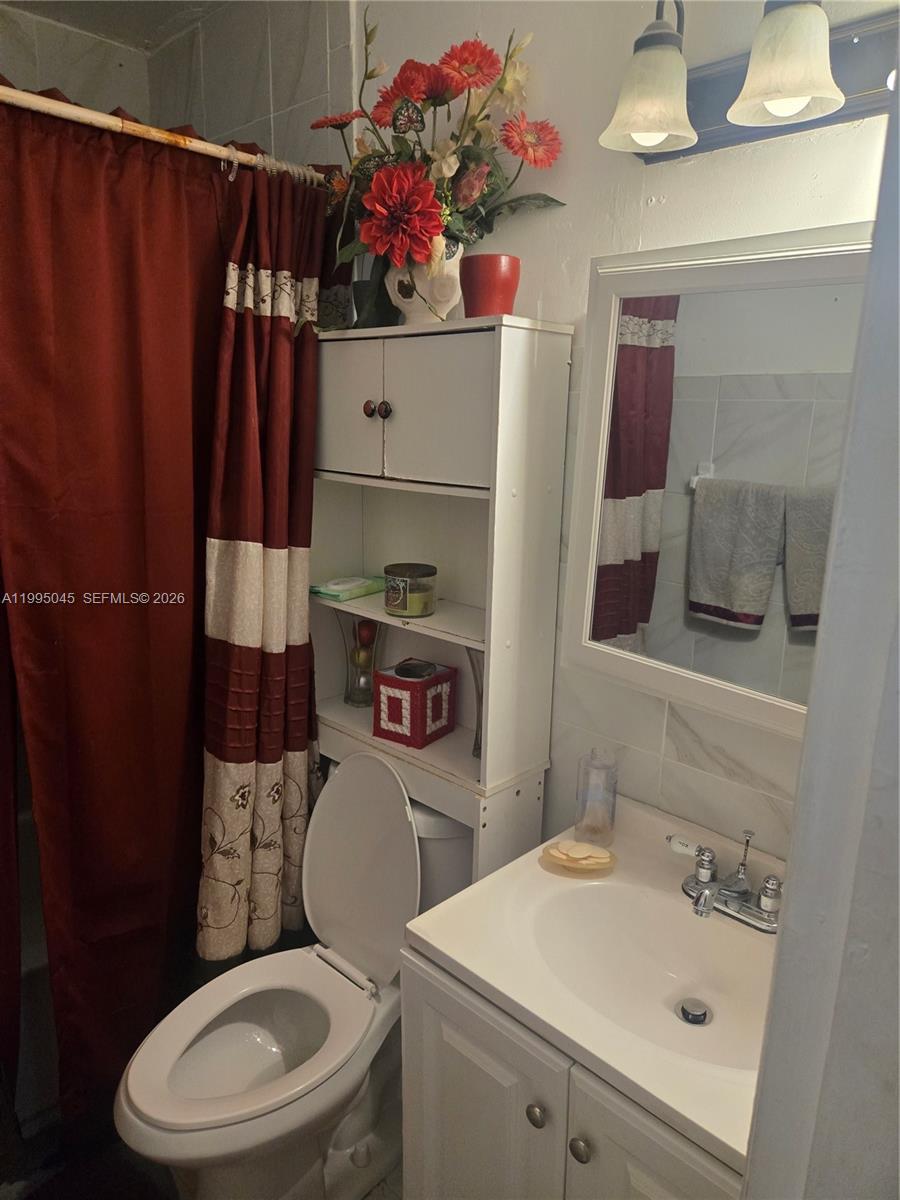 A bathroom features a white vanity, a toilet, an over-the-toilet storage unit, and red curtains — 10425 SW 146th Ter, Miami FL 33176, MIAMI, FL