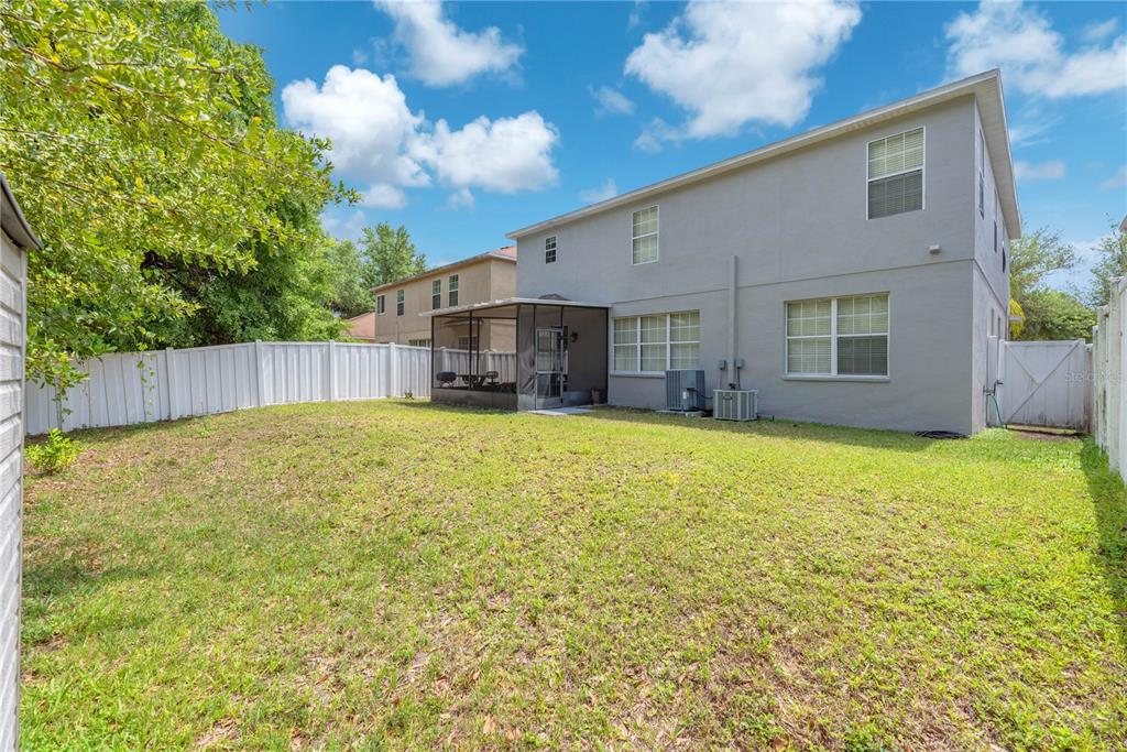A two-story house with a screened-in patio and a fenced backyard under a blue sky — 10638 DAWNS LIGHT DRIVE, RIVERVIEW, FL