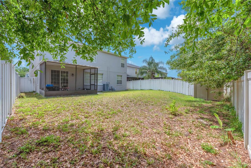 A backyard with a screened-in patio, a white vinyl fence, and a small storage shed — 10638 DAWNS LIGHT DRIVE, RIVERVIEW, FL