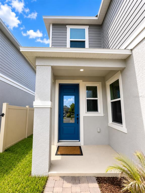 A blue front door with a glass panel is set under a covered porch entrance — 16522 BROOK ISLE WAY, CLERMONT, FL