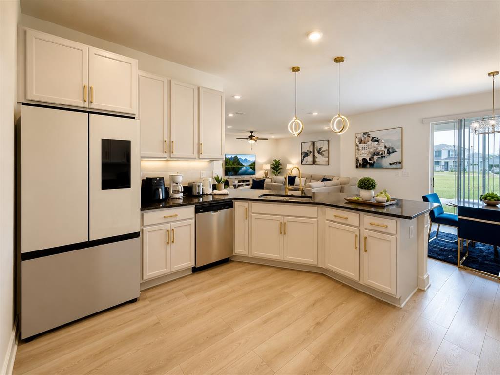 A modern kitchen features white cabinets, stainless steel appliances, and an island overlooking the living area — 16522 BROOK ISLE WAY, CLERMONT, FL