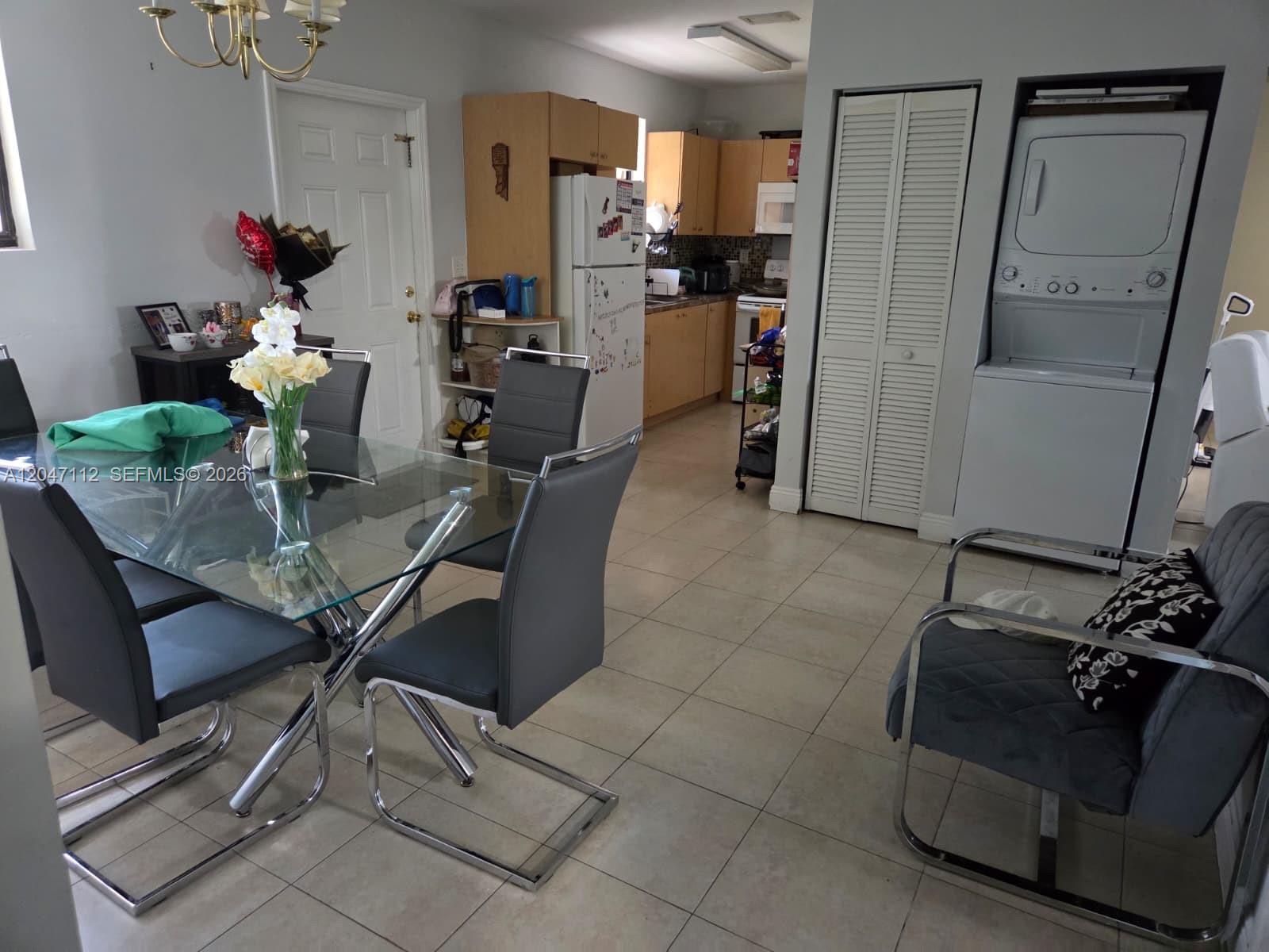A dining area with a glass table and chairs leads into a kitchen and laundry — 2816 NW 15th St # 2R, Miami FL 33125, MIAMI, FL