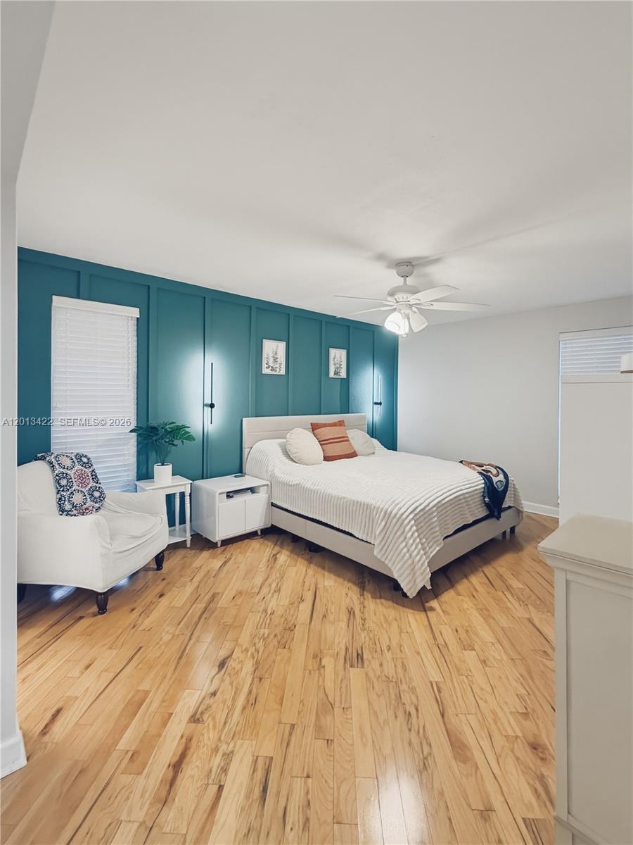 A bedroom features a teal board-and-batten accent wall, hardwood floors, and a white ceiling fan — 406 N Laurel Dr # 207, Margate FL 33063, MARGATE, FL