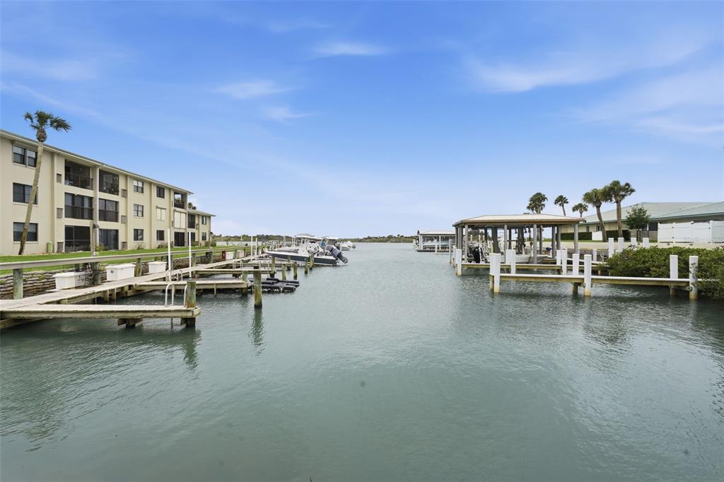 A view of a canal with boat docks and a multi-story apartment building — 2100 N PENINSULA AVENUE UNIT 1130, NEW SMYRNA BEACH, FL