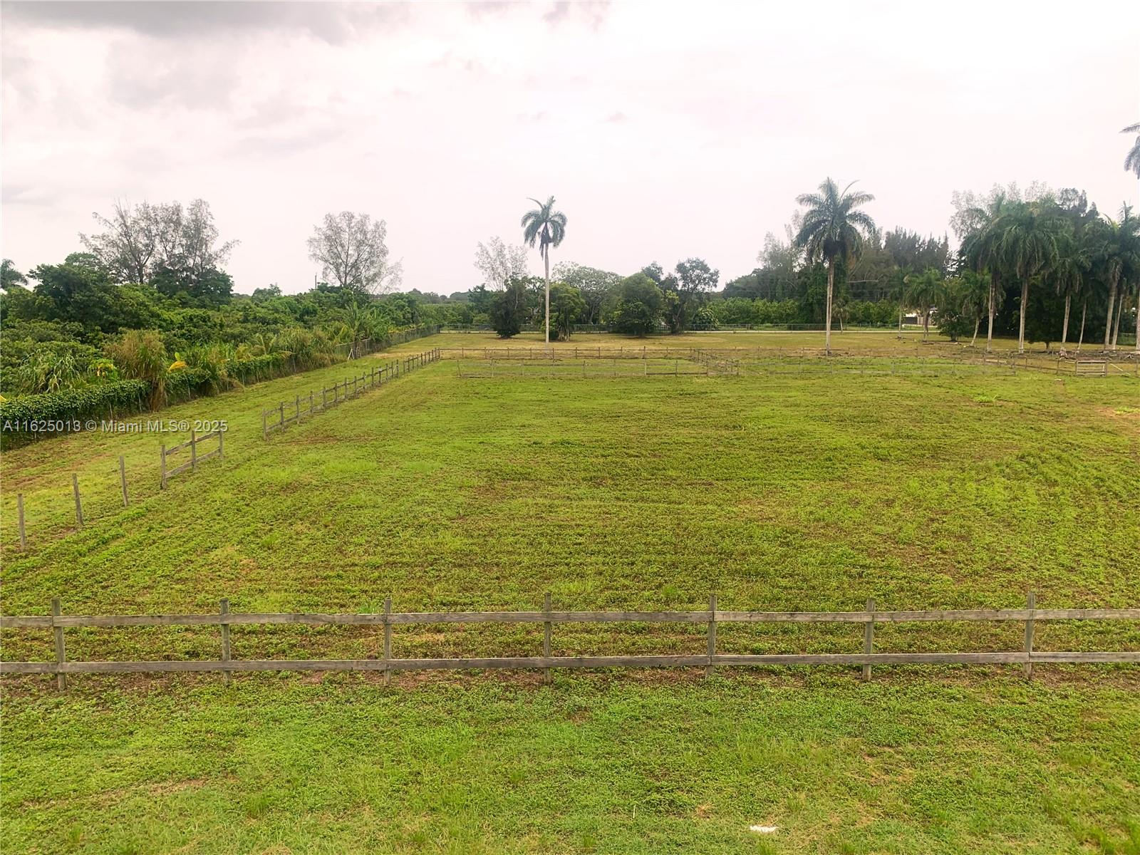 A large, grassy field is enclosed by wooden fences under a cloudy sky — 22750 SW 154th ave, Miami FL 33170, MIAMI, FL