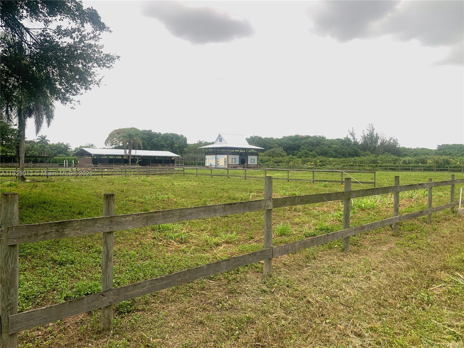 A fenced grassy pasture features a small house and a long barn in the distance — 22750 SW 154th ave, Miami FL 33170, MIAMI, FL