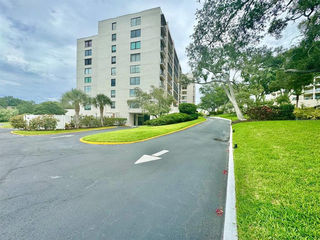 A multi-story apartment building stands behind a paved driveway with a directional arrow — 220 BELLEVIEW BOULEVARD UNIT 311, CLEARWATER, FL