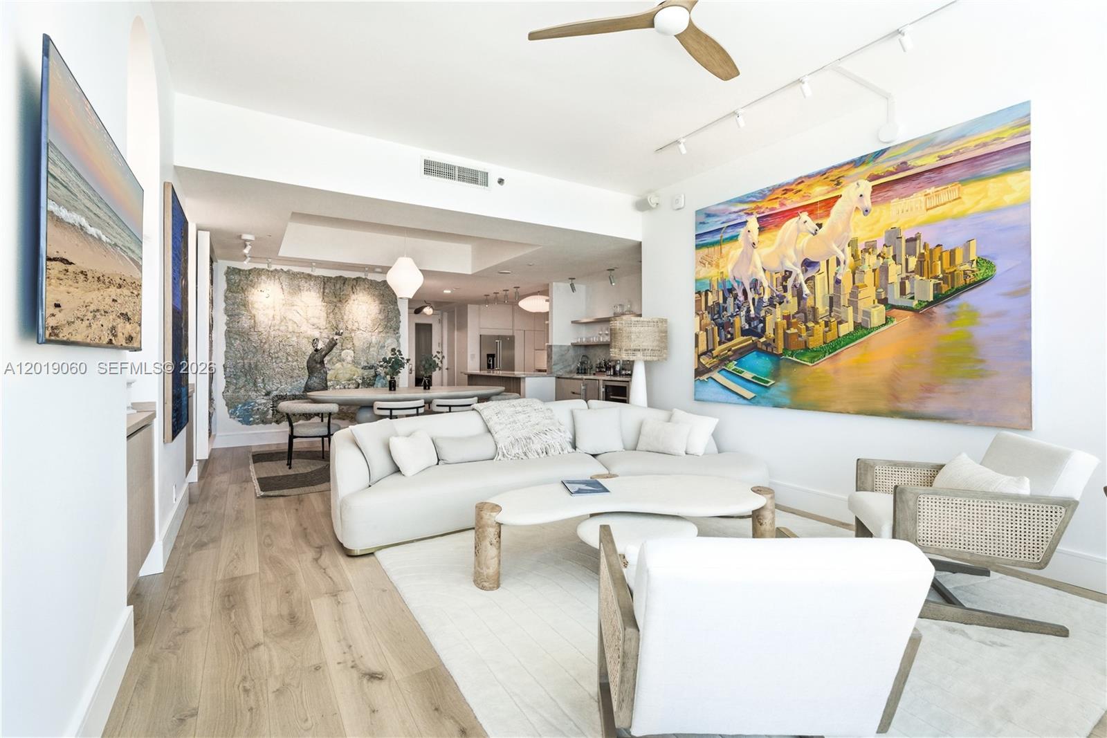 A modern living room features a white curved sofa, a large horse painting, and wood flooring — 100 S Pointe Dr # 1807, Miami Beach FL 33139, MIAMI BEACH, FL