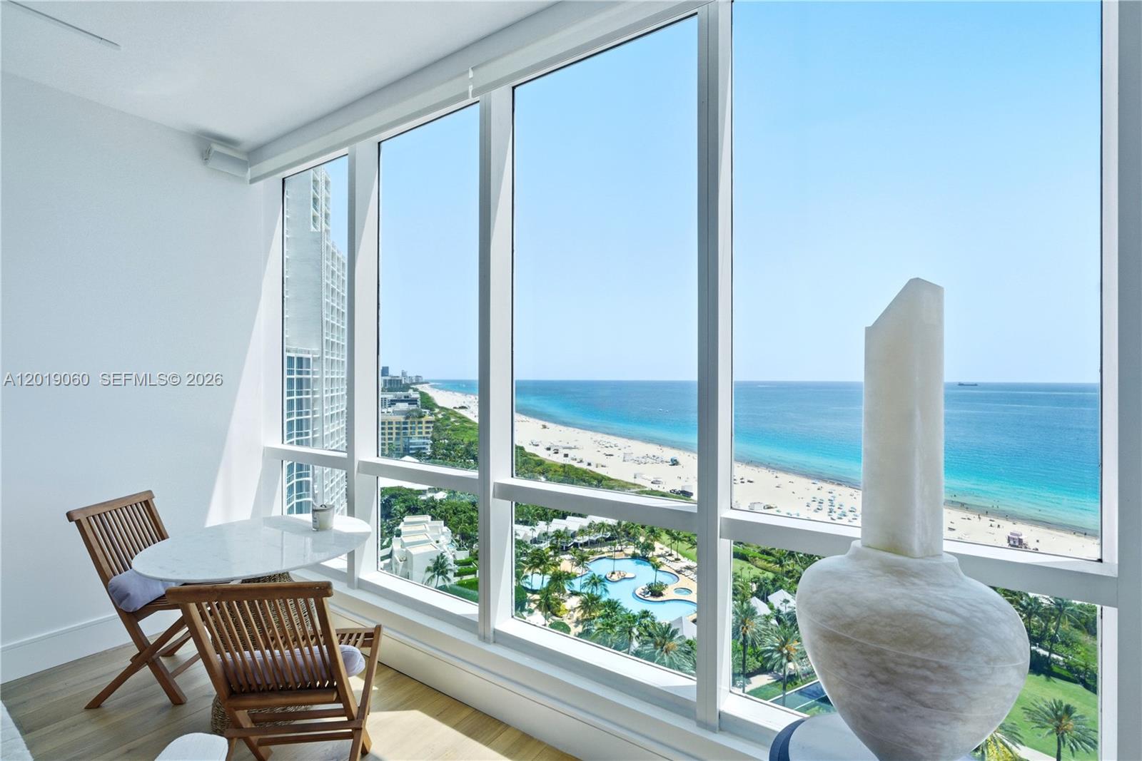 A sunroom with a small table and chairs overlooks a beach and ocean view — 100 S Pointe Dr # 1807, Miami Beach FL 33139, MIAMI BEACH, FL