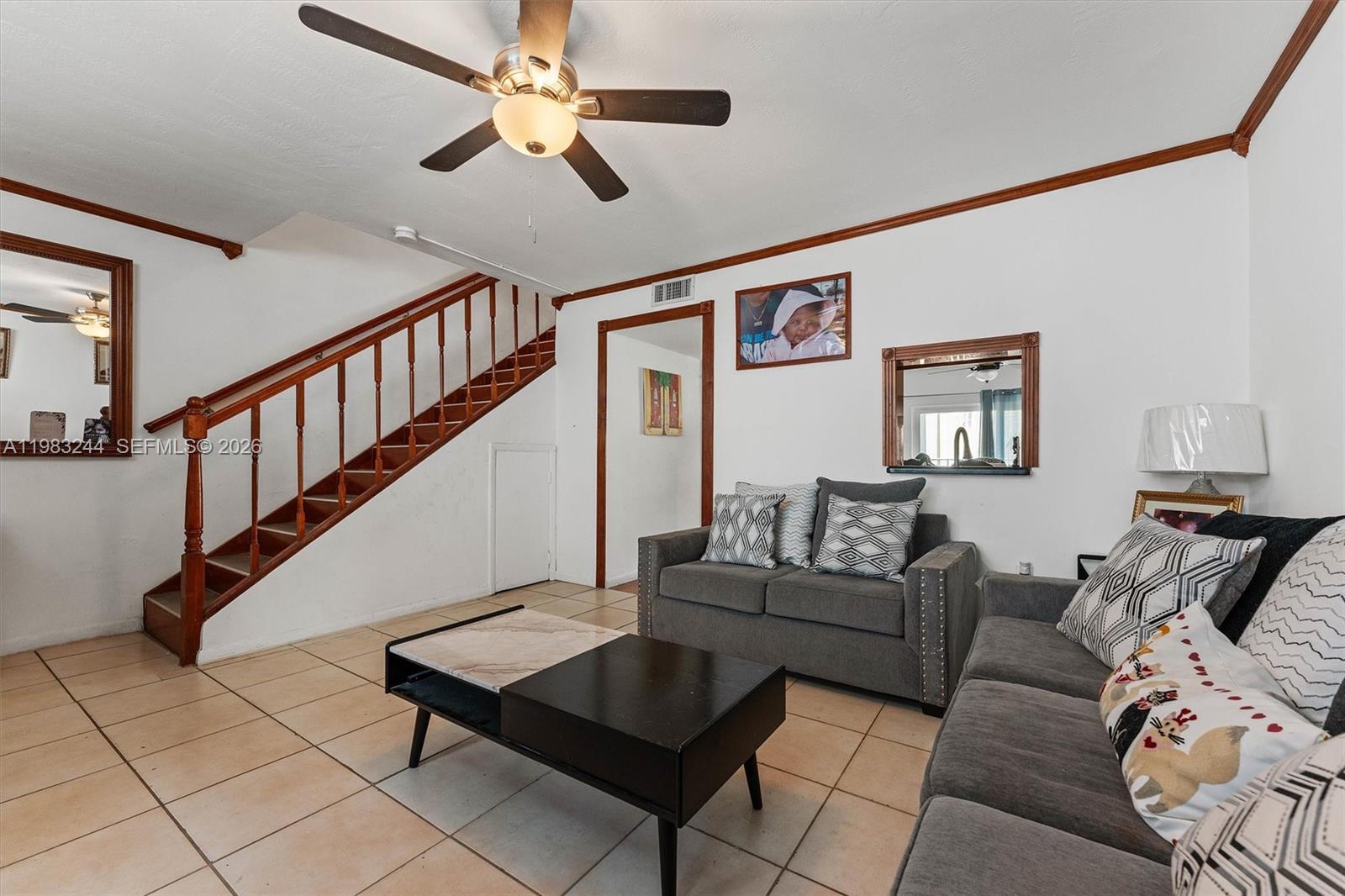 A living room features tile flooring, a wooden staircase, gray sofas, and a ceiling fan — 314 NE 142nd St # 16C, Miami FL 33161, MIAMI, FL