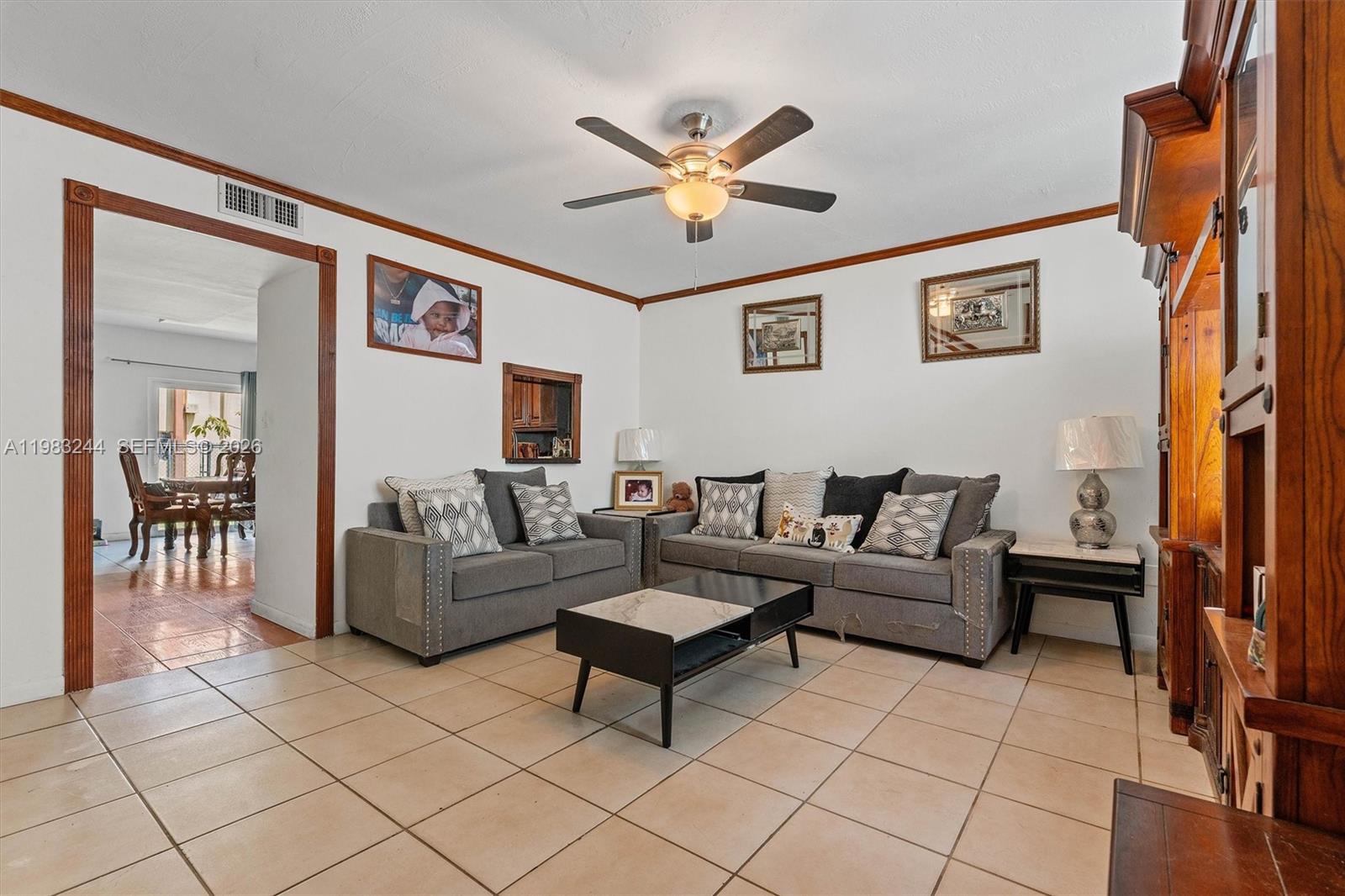 A living room features gray sofas, a coffee table, tile flooring, and wood trim — 314 NE 142nd St # 16C, Miami FL 33161, MIAMI, FL