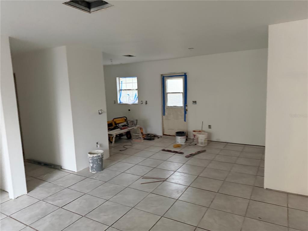 An unfinished room features white walls, light-colored floor tiles, a window, and a door — 5907 NW 64TH STREET, OCALA, FL