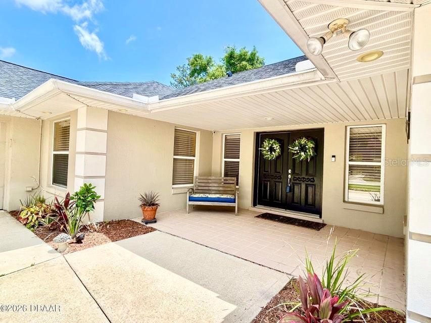 A covered entryway features a tiled patio, a wooden bench, and double front doors — 123 RIO PINAR DRIVE, ORMOND BEACH, FL