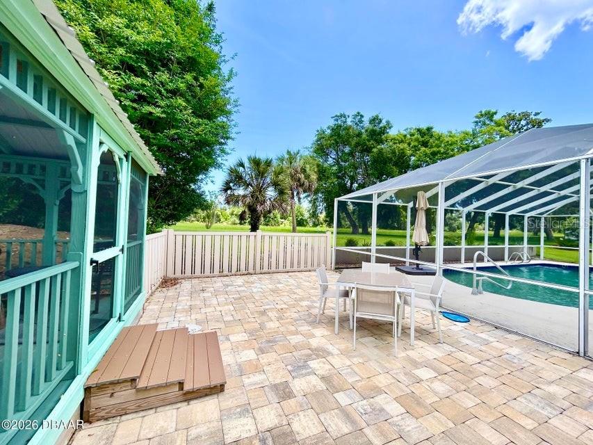 A paved patio features a screened pool enclosure, a gazebo, and a white fence — 123 RIO PINAR DRIVE, ORMOND BEACH, FL