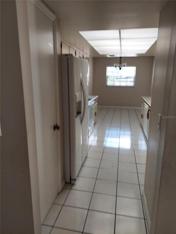A galley-style kitchen features white appliances, light-colored cabinets, and white tiled flooring — 8139 LAUREL TREE DRIVE, ORLANDO, FL
