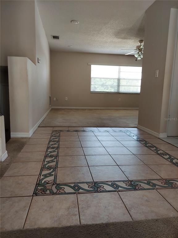 A tiled entryway with a decorative border leads into a carpeted living area with windows — 8139 LAUREL TREE DRIVE, ORLANDO, FL