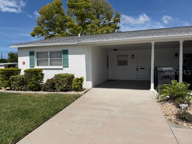 A white single-story house features a carport, teal shutters, and a small front yard — 5973 HIBISCUS DRIVE, BRADENTON, FL
