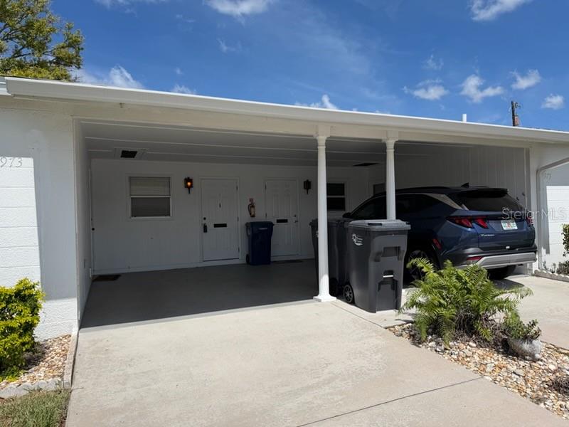 A white single-story house features a concrete driveway, a covered carport, and teal window shutters — 5973 HIBISCUS DRIVE, BRADENTON, FL
