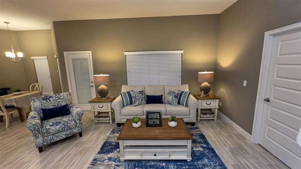 A living room features a beige sofa, patterned armchair, wooden coffee table, and blue rug — 29 MATRICARIA COURT, HOMOSASSA, FL