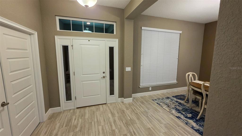 An entryway features a white front door with sidelights, wood-look tile flooring, and a dining area — 29 MATRICARIA COURT, HOMOSASSA, FL