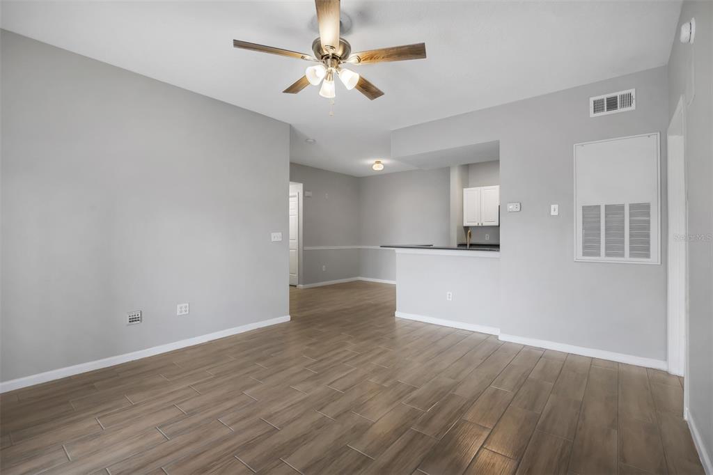 A living room with wood-look tile flooring, a ceiling fan, and an open kitchen area — 14316 FREDRICKSBURG DRIVE UNIT 518, ORLANDO, FL