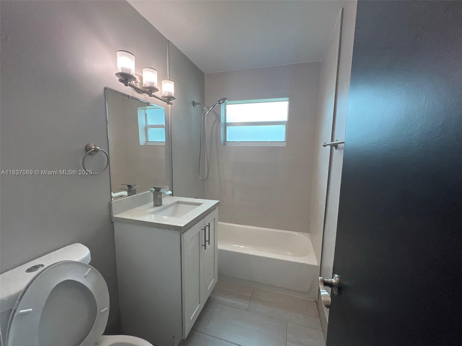 A bathroom features a white vanity, a toilet, and a bathtub with a shower head — 2569 NW 61st Ave, Margate FL 33063, MARGATE, FL
