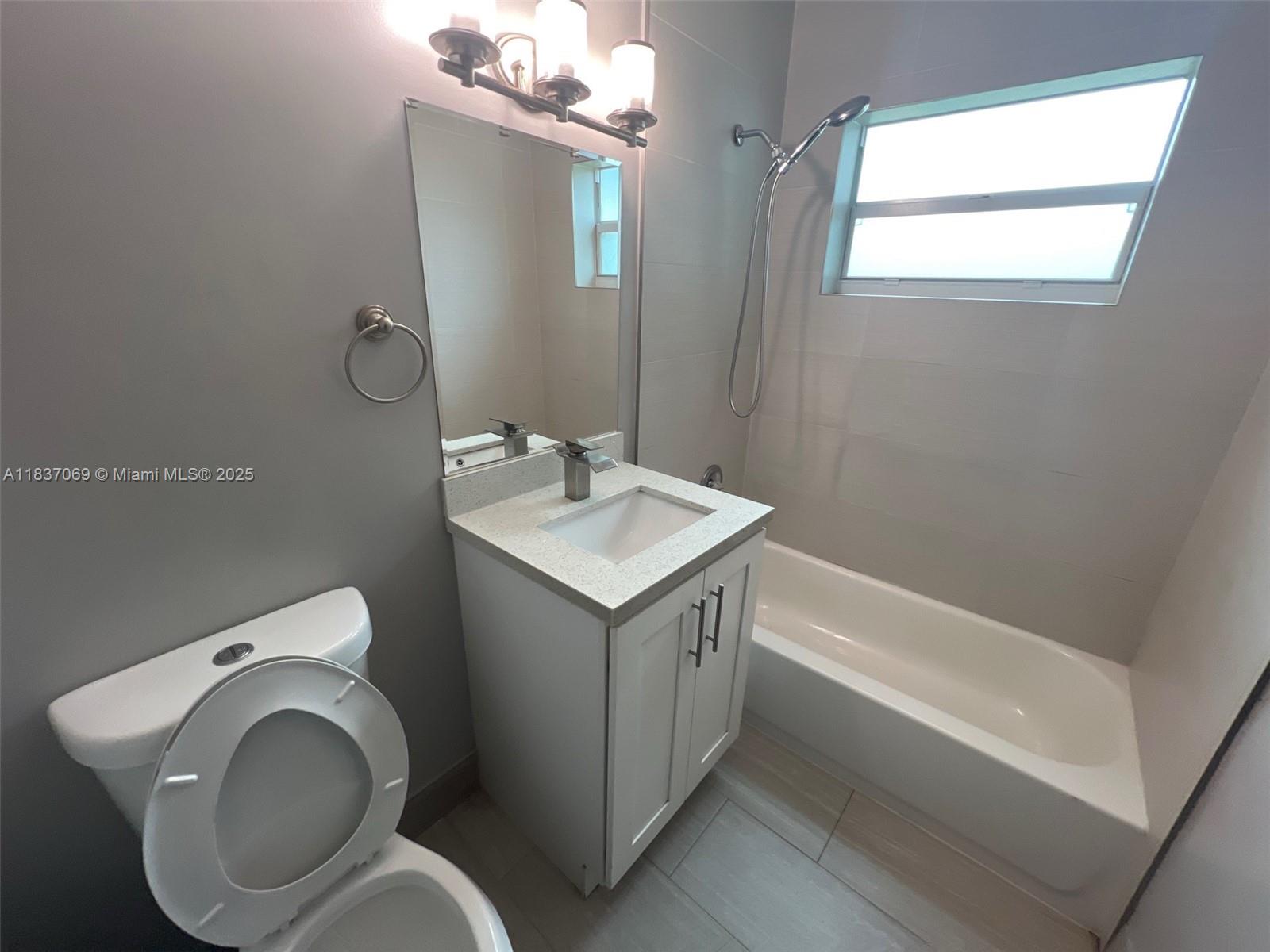 A bathroom features a white vanity, a toilet, and a bathtub with a shower head — 2569 NW 61st Ave, Margate FL 33063, MARGATE, FL